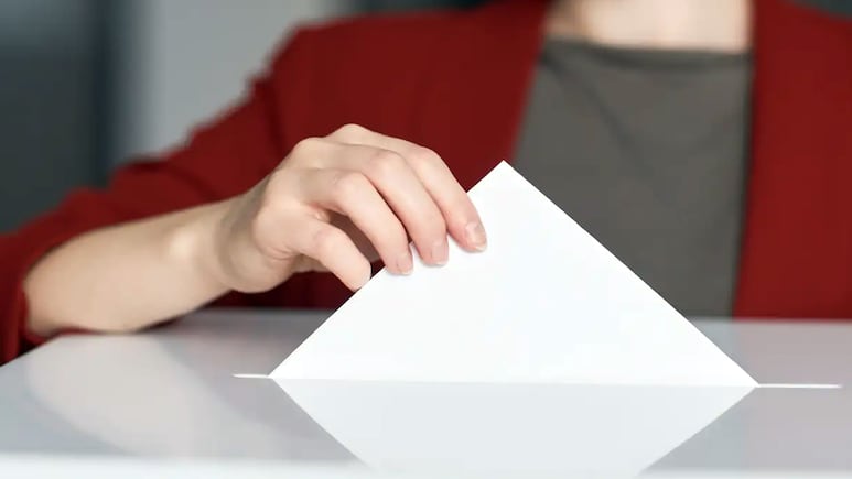 Elecciones (persona colocando su voto en la urna)