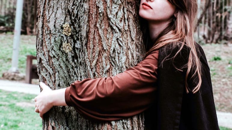 Mujer abrazada a un árbol.