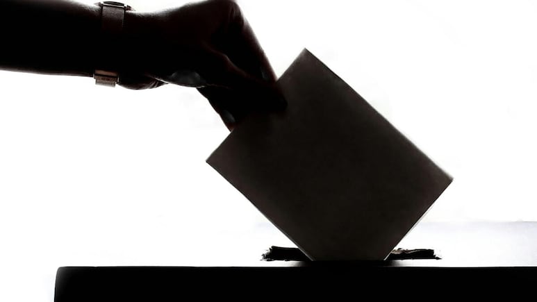 Elecciones (persona colocando su voto en la urna).