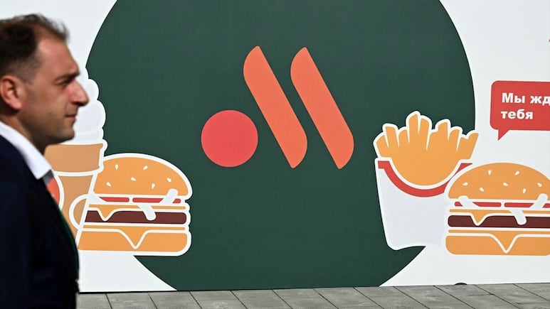 Persona pasa enfrente de un anuncio de Vkusno i tochka, versión rusa de McDonalds.